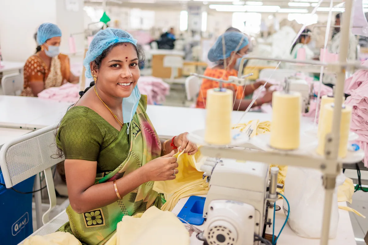 A smiling woman working in garment production at Cossmo Tex