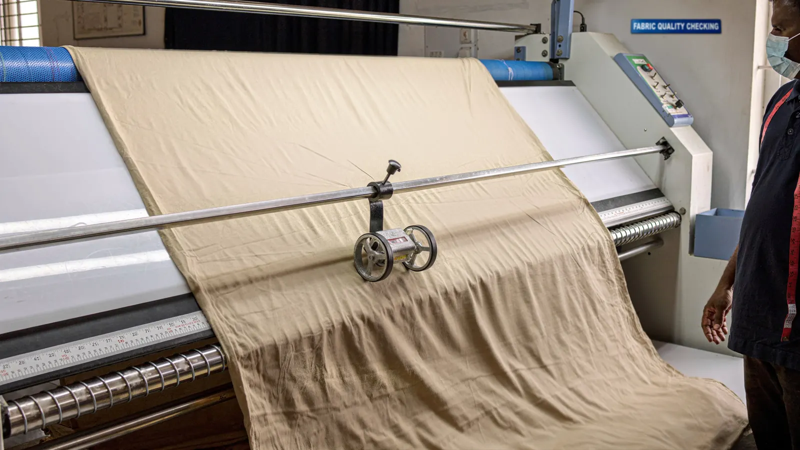 Fabric passing through quality inspection equipment at Cossmo Tex